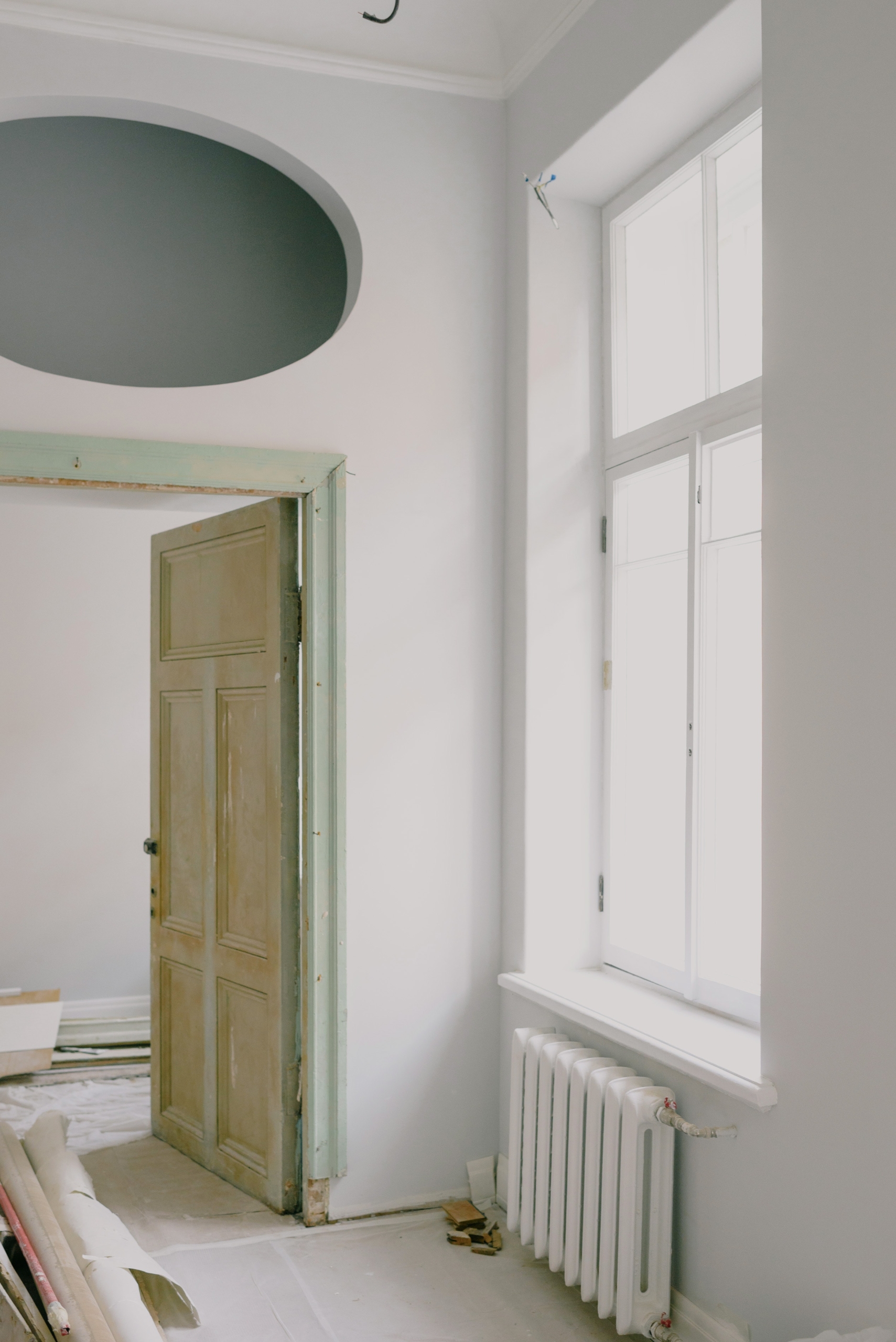 Imagen de una ventana con puerta y radiador clásico con materiales de obra en el suelo indicando reforma integral de una vivienda.